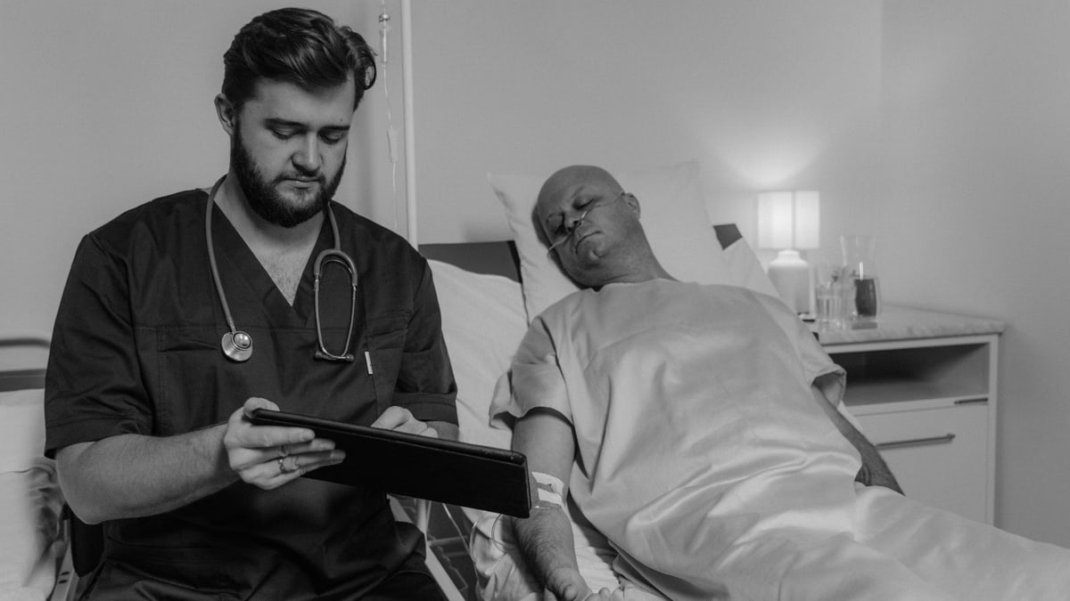 Doctor reviewing patient's data on a tablet in a hospital room.