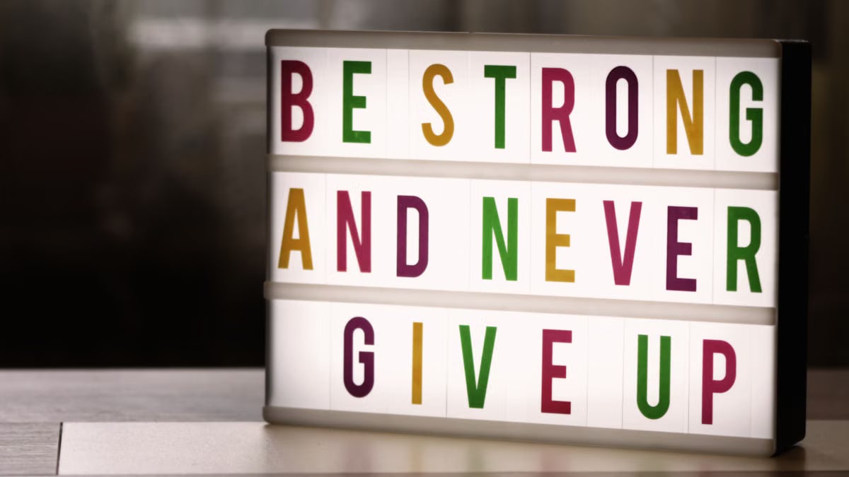 Inspirational lightbox displaying the motivational quote 'Be Strong and Never Give Up' indoors.